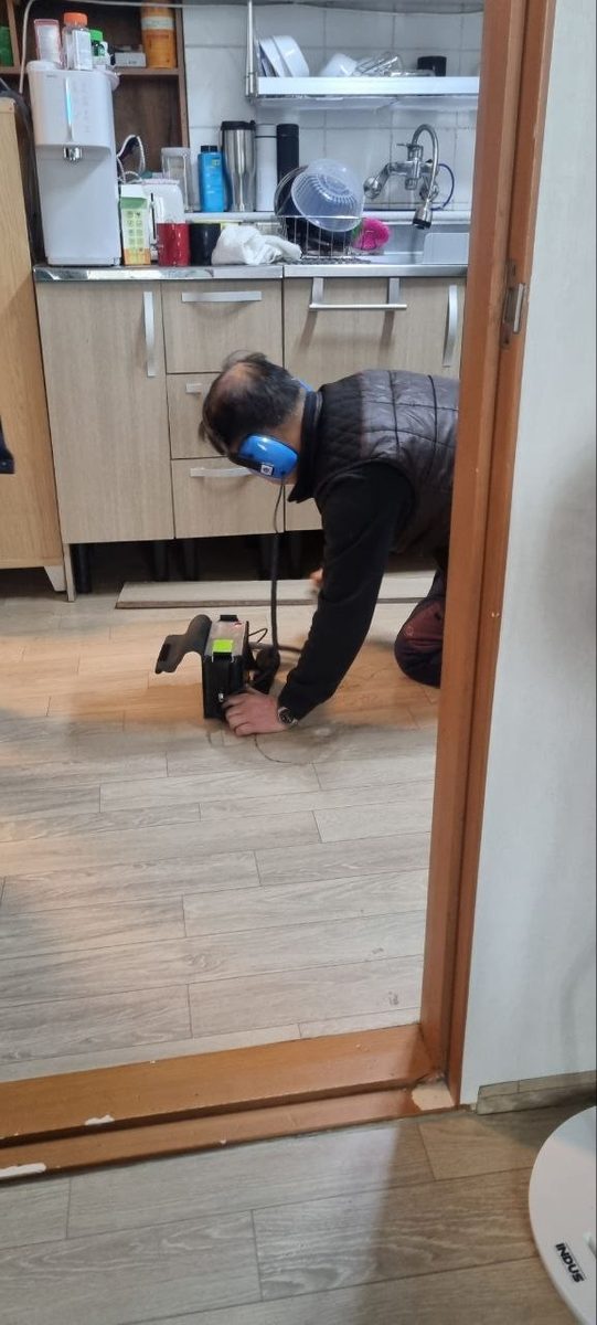 주방 마루 바닥에 센서를 대고 싱크대 아래로 이어지는 배관 구간을 확인하는 현장 사진